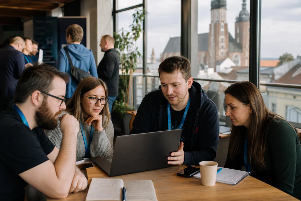 A group of coworkers collaborating around a laptop at a table in a bright office