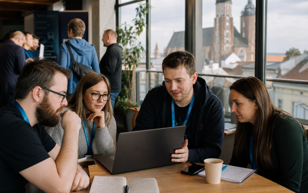 A group of coworkers collaborating around a laptop at a table in a bright office